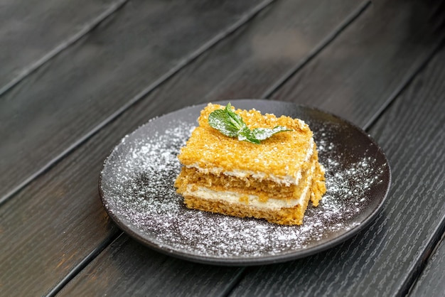 Ein Stück Honigkuchen mit Buttercreme, garniert mit Puderzucker und Minze