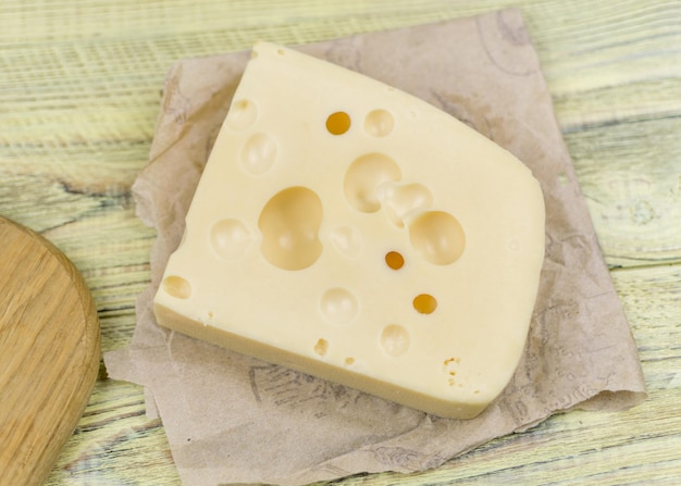 Ein Stück Käse mit großen Löchern auf einem Holzschneidebrett