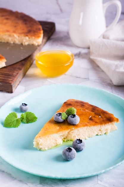 Ein Stück Käsekuchen mit Honig und Heidelbeeren auf einem Teller Hausgemachtes Gebäck Vertikale Ansicht