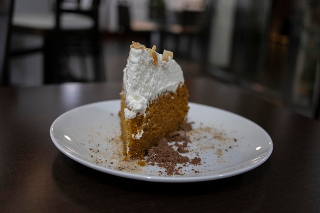 Ein Stück Karottenkuchen mit Sahne bedeckt Selektiver Fokus Im Hintergrund die Cafeteria