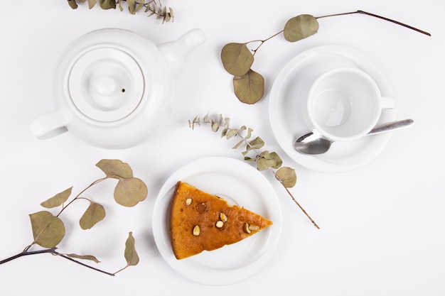 Ein Stück Kuchen auf einer Untertasse mit einer Tasse für Tee oder Kaffee und einem Wasserkocher