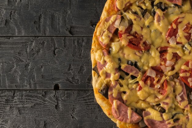 Ein Stück Pizza auf einem schwarzen Holztisch. Traditionelle italienische Küche. Der Blick von oben.