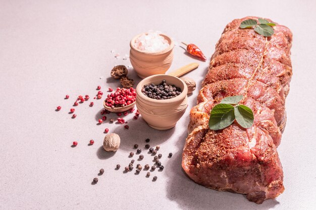 Ein Stück rohe Schweinelende. Mariniertes Frischfleisch mit kulinarischer Schnur mit Gewürzen gebunden. Ein trendiges hartes Licht, dunkler Schatten, Steinbetonhintergrund, Kopierraum