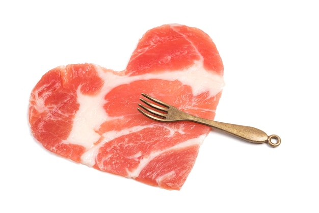 Ein Stück rohes Fleisch in Form eines Herzens und einer kleinen Gabel isoliert