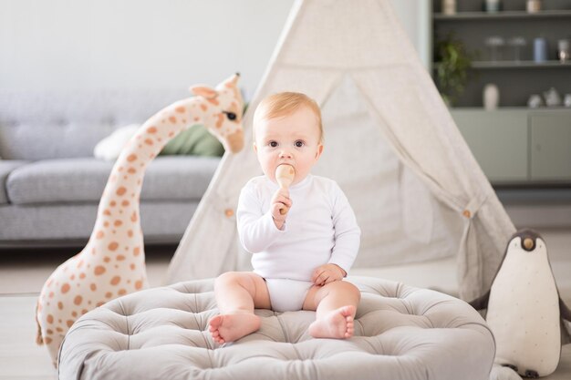 Ein süßer, gesunder Junge in einem geräumigen, hellen Kinderzimmer zu Hause mit einem Wigwam Stofftiere Kindertextilien Ein Kind spielt im Wohnzimmer des Hauses