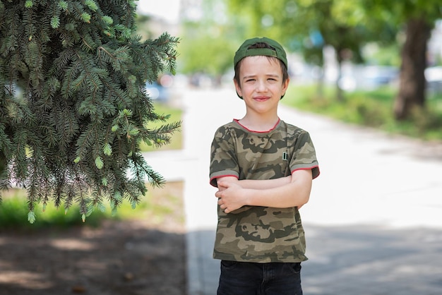 Ein süßer Junge in einem T-Shirt mit Militäraufdruck und einer Mütze