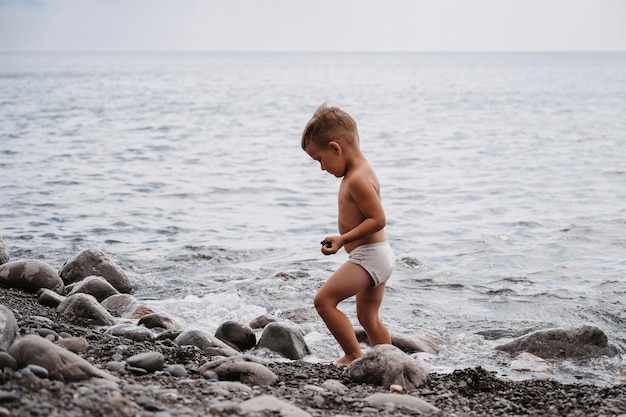 Ein süßer Junge läuft an der Küste entlang am Strand Outdoor-Aktivitäten