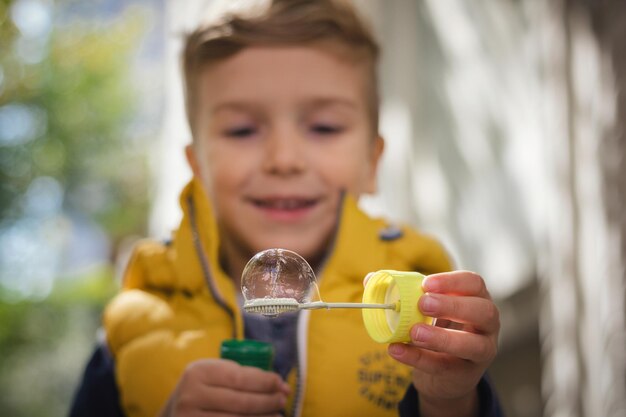 Foto ein süßer junge mit einem bubble-stab im freien