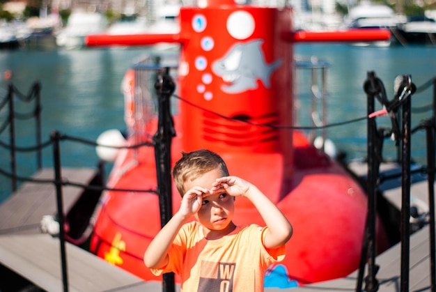 Ein süßer Junge schützt seine Augen, während er den Hafen abblickt.