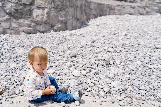 Ein süßer Junge sitzt auf einem Felsen