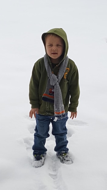Foto ein süßer junge steht auf dem schnee
