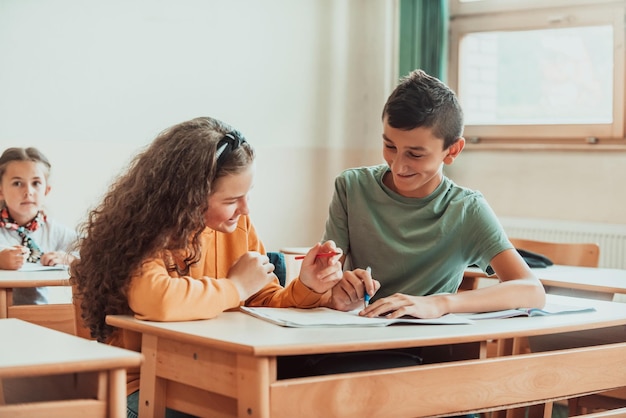 Ein süßer Junge und ein Mädchen saßen auf einer Schulbank und arbeiteten in der Klasse zusammen. Selektiver Fokus Foto in hoher Qualität