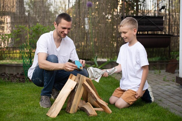 Ein süßer Junge und sein Vater zünden ein Feuer mit weißen T-Shirts an