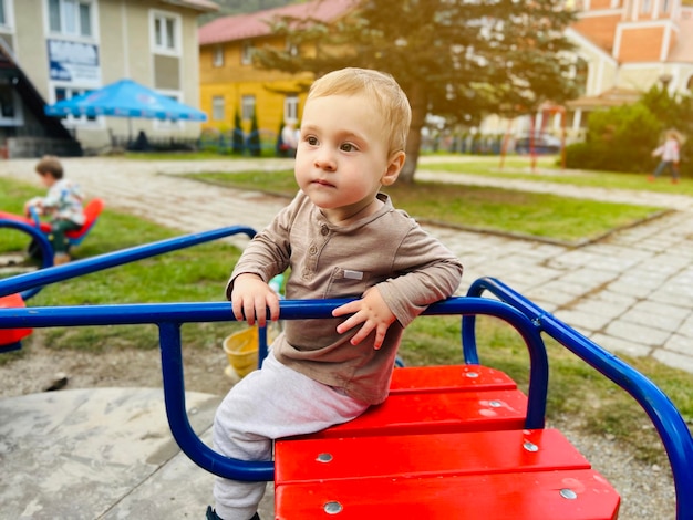 Ein süßer Junge von anderthalb Jahren reitet auf einer Schaukel auf dem Spielplatz Kinderunterhaltung Selektiver Fokus