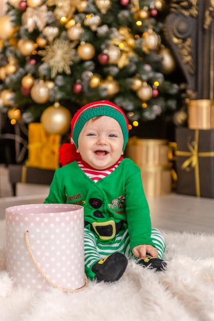 Ein süßer kleiner Junge, der als Elf verkleidet ist, öffnet ein Weihnachtsgeschenk in einem geschmückten Weihnachtshaus.