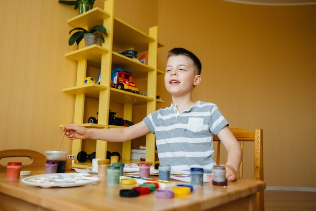 Ein süßer kleiner Junge spielt und malt in seinem Zimmer. Erholung und Unterhaltung. Bleib zuhause.