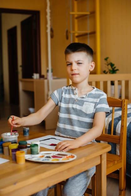 Ein süßer kleiner Junge spielt und malt in seinem Zimmer