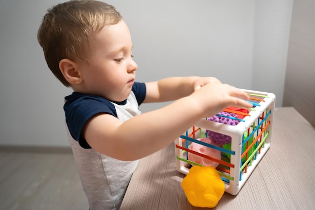 Ein süßer Kleinkindjunge spielt ein Spiel mit sensorischen bunten Bällen Sensorische und taktile Aktivitäten Spiele für Kinder eineinhalb Jahre alt Aufmerksames Kind Konzentrieren Sie sich auf die Augen