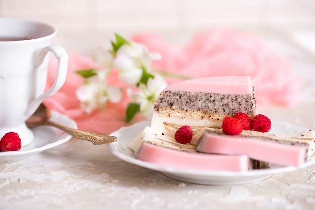 Ein süßer rosa Rosentassenkuchen mit Teekanne und Tasse auf dem Tisch