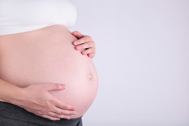 Ein süßer schwangerer Bauch auf einem Grau