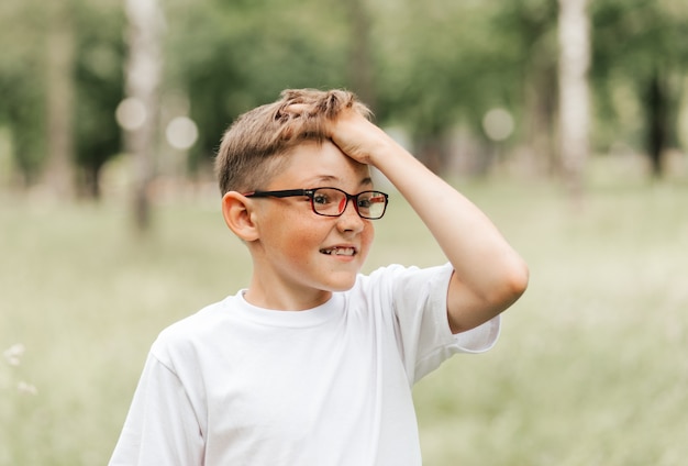 Ein süßer sommersprossiger Junge mit Brille hält sich an seinem Kopf fest.