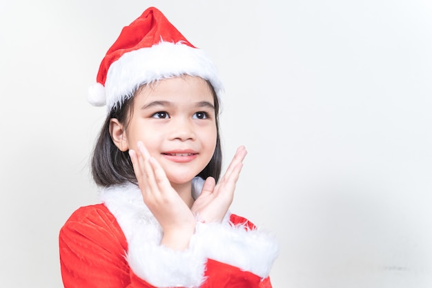 Ein süßes asiatisches kleines Mädchen in einem roten Weihnachtsmann-Kleid, das den Weihnachtsbaum an Heiligabend schmückt