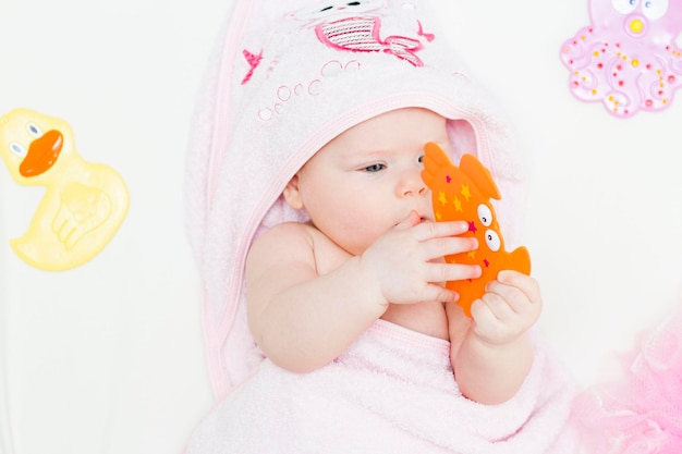 Ein süßes Baby liegt nach einem Bad in einem rosa Handtuch Baden von Neugeborenen