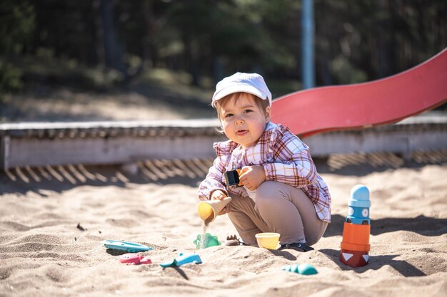 Ein süßes Baby spielt mit Spielzeug im Sand am Strand an einem sonnigen Sommertag