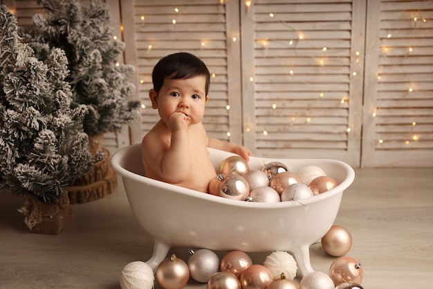 Ein süßes dunkelhäutiges Mädchen sitzt in einer Badewanne mit Weihnachtsbaumspielzeug