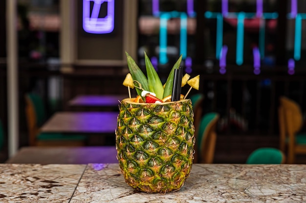 Ein süßes, fruchtiges, tropisches, alkoholisches Cocktail-Rum-Getränk, das in einer Ananas an der Bar serviert wird