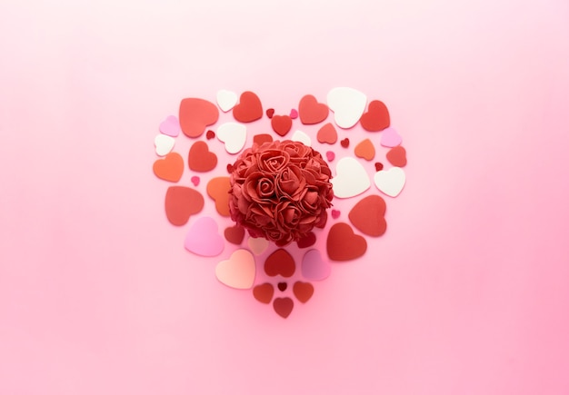 Ein süßes Herz aus Herzen mit einer rot zentrierten Rose in einem rosa Hintergrund für Valentinstag