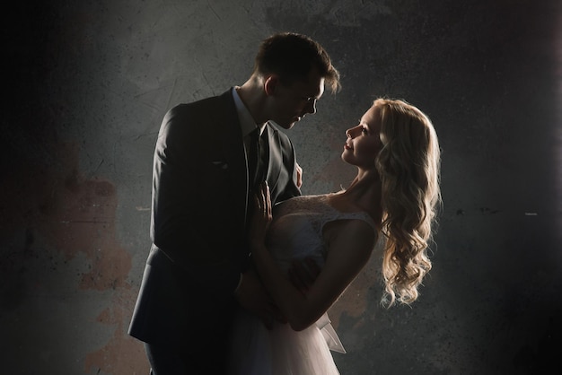 Ein süßes Hochzeitspaar im Inneren eines klassisch eingerichteten Studios küsst und umarmt sich