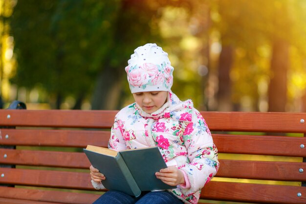 Ein süßes Kind liest ein Buch im Park.