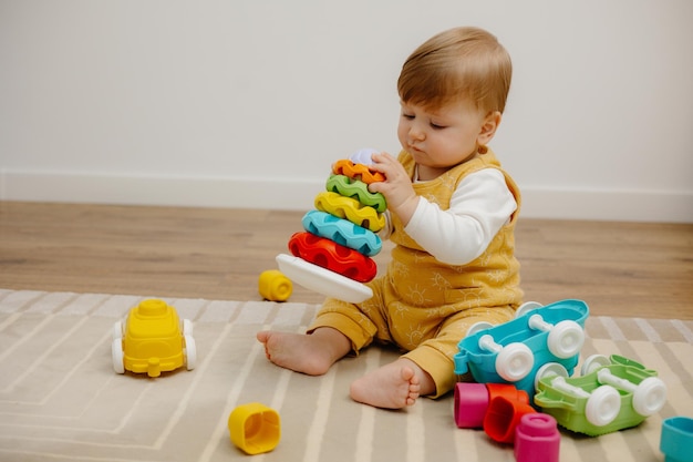 Ein süßes Kind spielt mit einer bunten Regenbogen-Spielzeugpyramide Spielzeug für kleine Kinder