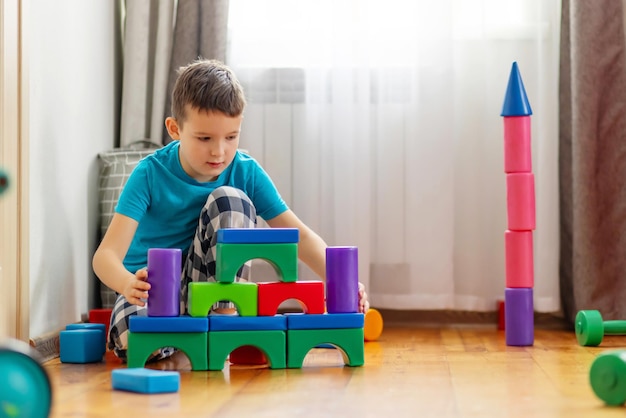 Ein süßes kleines Kind, das mit bunten Plastikspielzeug oder -blöcken spielt