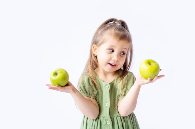 Ein süßes kleines Mädchen hält einen großen grünen Apfel in ihren Händen Weißer isolierter Hintergrund Gesunde Lebensmittel für Kinder oder ein gesunder Snack Platz für Text Hochwertige Fotografie