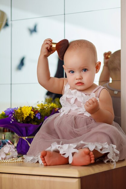 Ein süßes kleines Mädchen hält einen Make-up-Pinsel und hat Spaß zu Hause