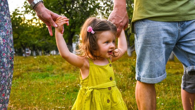 Foto ein süßes kleines mädchen hält sich mit seinem vater an die hand, geht mit kindern spazieren und hält ein kleines mädchen in der hand.