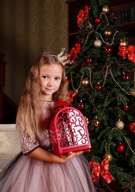 Ein süßes kleines mädchen in einem kleid, das sich auf neujahr vorbereitet. in erwartung der partei,