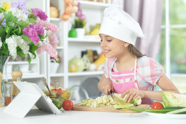 Ein süßes kleines Mädchen macht zu Hause Abendessen auf dem Küchentisch