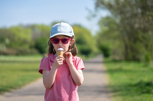 Foto ein süßes kleines mädchen mit sonnenbrille genießt eis im park.