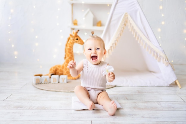 Ein süßes kleines Mädchen sitzt in einem hellen, gemütlichen Kinderspielzimmer Textilien für Kinder für das Kinderzimmer Ein glückliches Kind