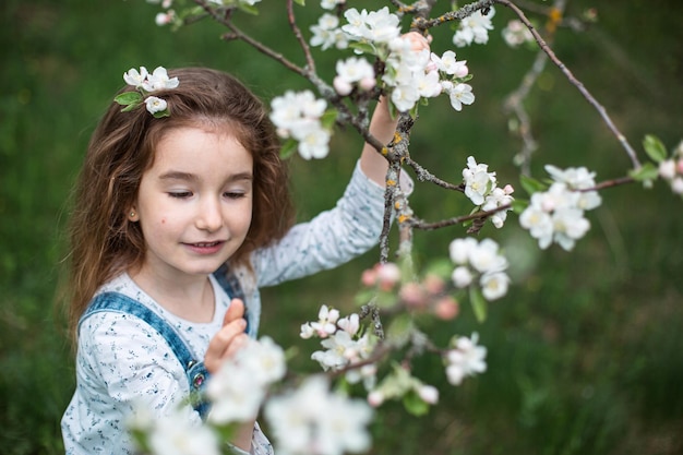 Ein süßes kleines Mädchen von 5 Jahren in einem blühenden weißen Apfelgarten im Frühling Frühlingsgarten blühende Allergie Frühlingsduft Zärtlichkeit Pflege der Natur Portrait