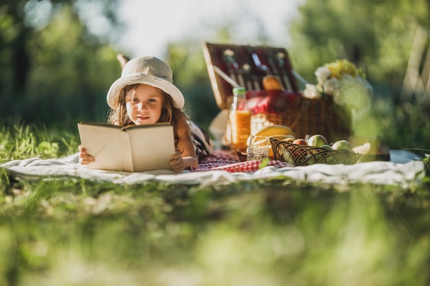 Ein süßes Lächeln, das einen Frühlingstag in der Natur verbringt und ein Buch über ein Picknick liest.