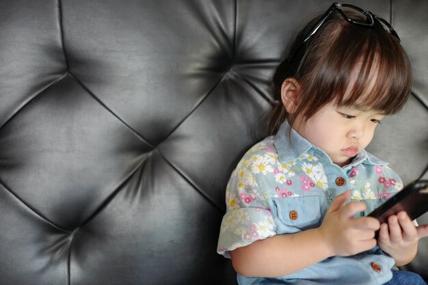 Foto ein süßes mädchen benutzt ein smartphone auf dem sofa