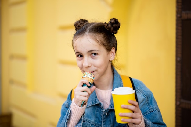 Ein süßes Mädchen isst Eis und trinkt Tee außerhalb Takeaway Kindheit Das Konzept des leckeren Essens