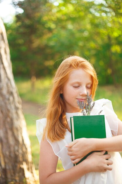 Ein süßes Mädchen mit einem Buch und Blumen