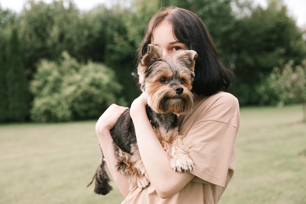 Ein süßes Mädchen mit einem Yorkshire-Terrier auf der Straße Umarmungen mit Ihrem kleinen Hund im Park