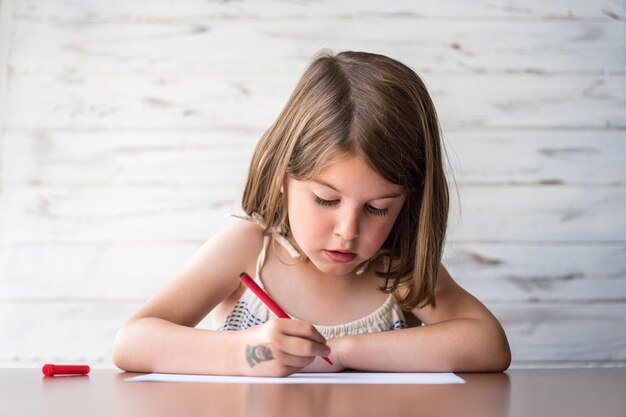 Ein süßes Mädchen schreibt zu Hause auf Papier