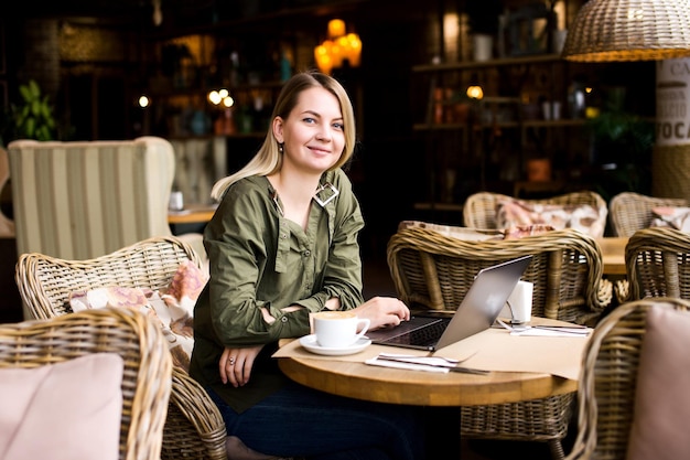 Ein süßes Mädchen trinkt Kaffee und arbeitet an einem Laptop Fernarbeit